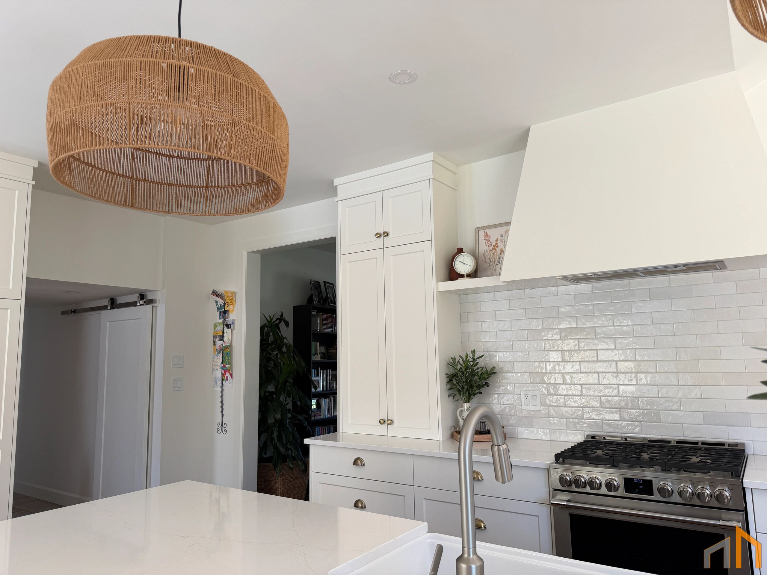 Bright modern kitchen with white cabinets and a wicker pendant light.
