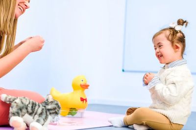 A woman and a child happily playing with toys indoors.