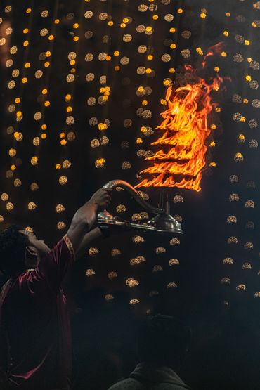 Person holding a flaming lamp during a ritual.