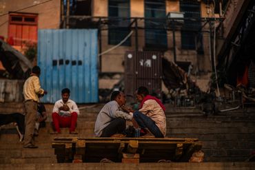 Men sitting and talking on steps in an urban area.