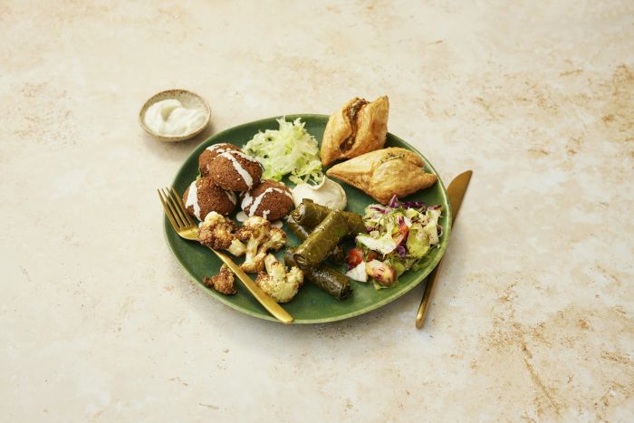 A grazing table of cold and hot mezze: hummus, falafel, vine leaves and salad