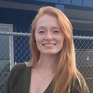 Smiling woman with long red hair wearing a green cardigan.