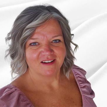 Smiling woman with gray hair wearing a purple top against a white background.