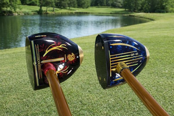 Two vintage golf clubs with wooden shafts on a grassy course near a pond.