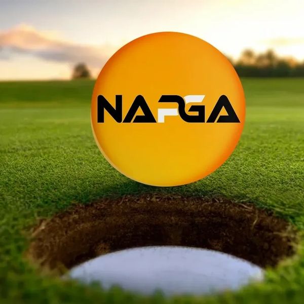 An orange golf ball with 'NAPGA' logo near a hole on a golf course.