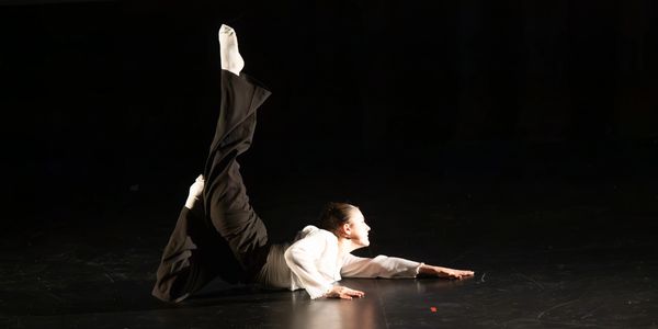 Danseur allongé au sol, une jambe levée.