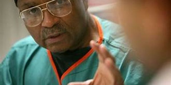 A man in medical scrubs speaking intently.
