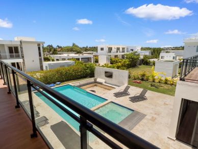 View of a modern residential pool area with lounge chairs and clear sky.