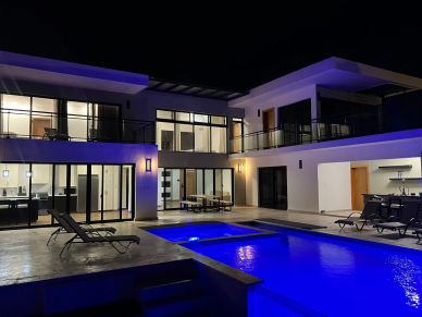 Modern house with illuminated pool and patio at night.