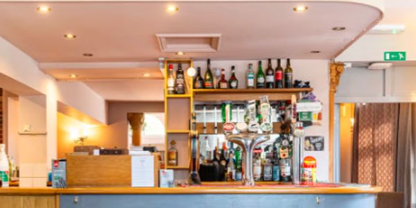 Empty modern bar counter with various bottles and taps.