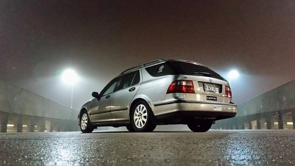 Silver station wagon parked on wet pavement at night under streetlights.