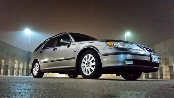 Silver station wagon parked in a dimly lit urban area at night.