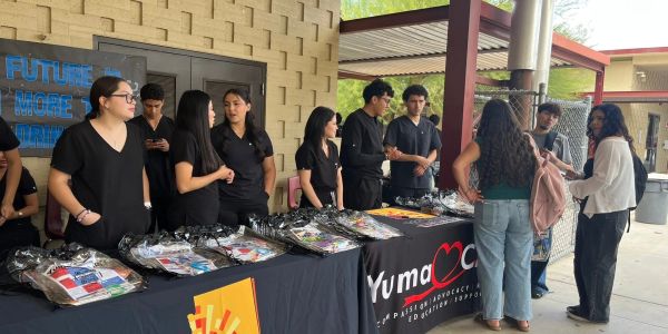 Group of volunteers at an outdoor information booth with Yuma advocacy banners.