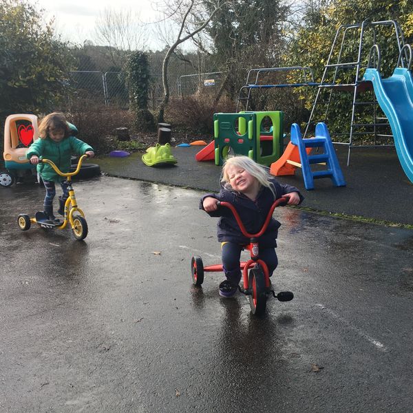 Children enjoying themselves outside at Avening playgroup in the playground.