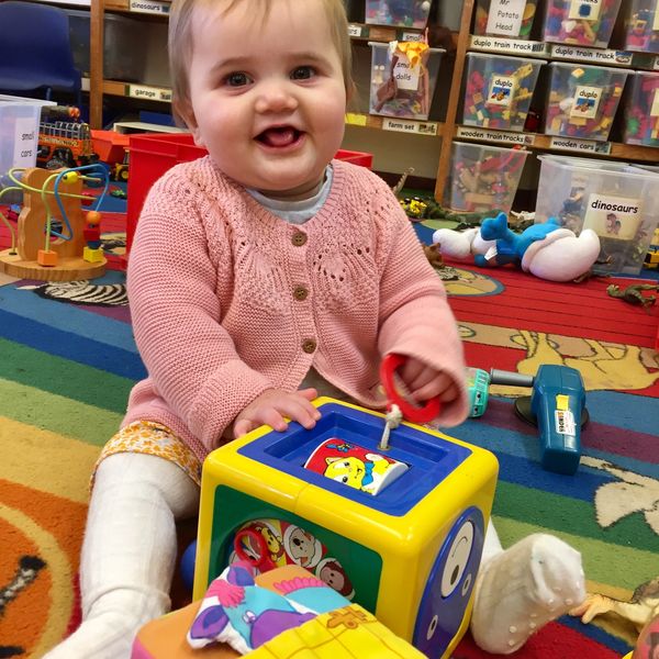 A baby at toddler group playing with a toy.