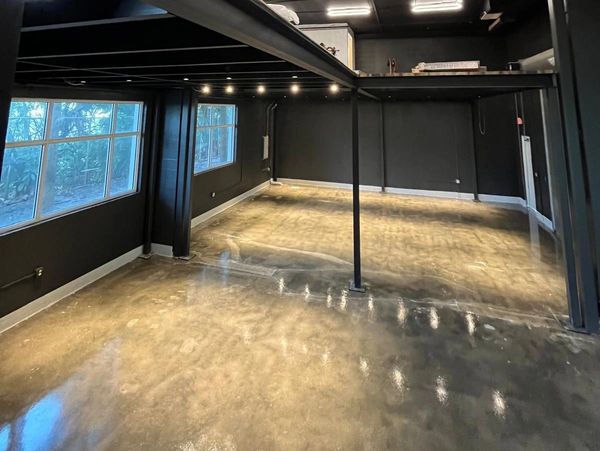 Empty industrial-style room with polished concrete floor and black walls.