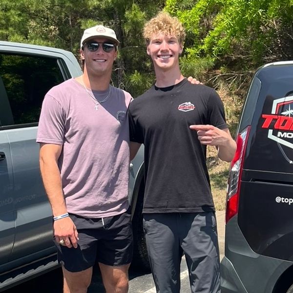 Two young men posing and smiling outdoors.