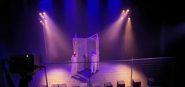 Two people on stage with spotlight and industrial screen.