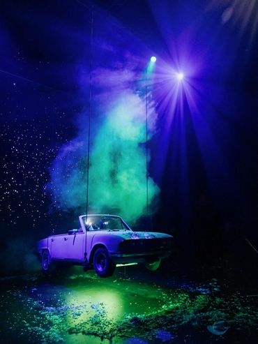 A purple convertible car suspended with green and blue lights.