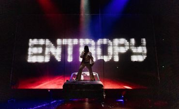 Silhouette of a performer with 'ENTROPY' lit up behind.