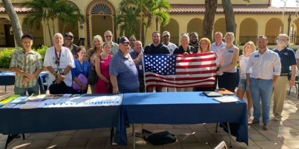 Group photo with American flag at an outdoor event.