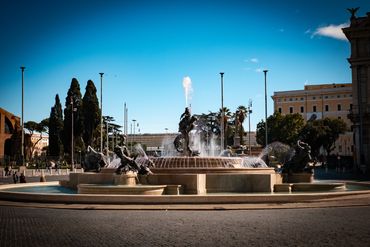 A grand fountain with statues of horses and mythological figures under a clear blue sky.