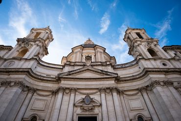 Baroque church facade with two bell towers under a blue sky.