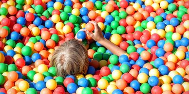 child buried in multi-colored ball pit