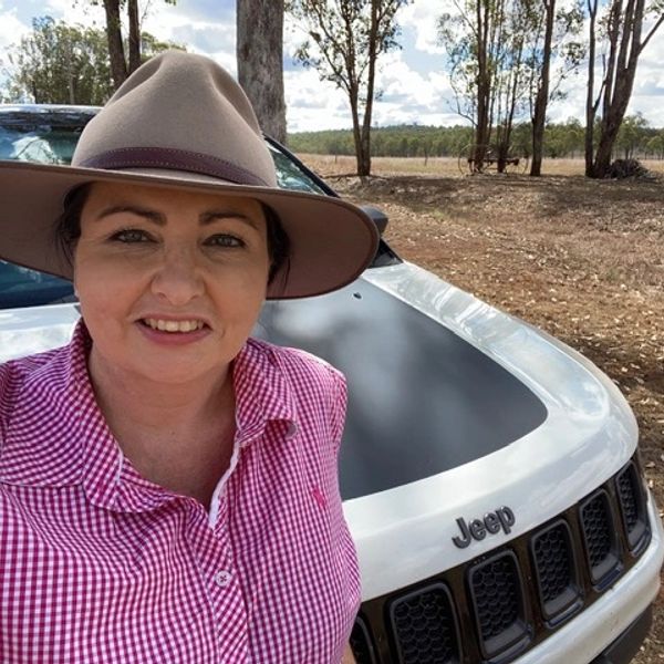 Woman in a hat standing by a Jeep outdoors.