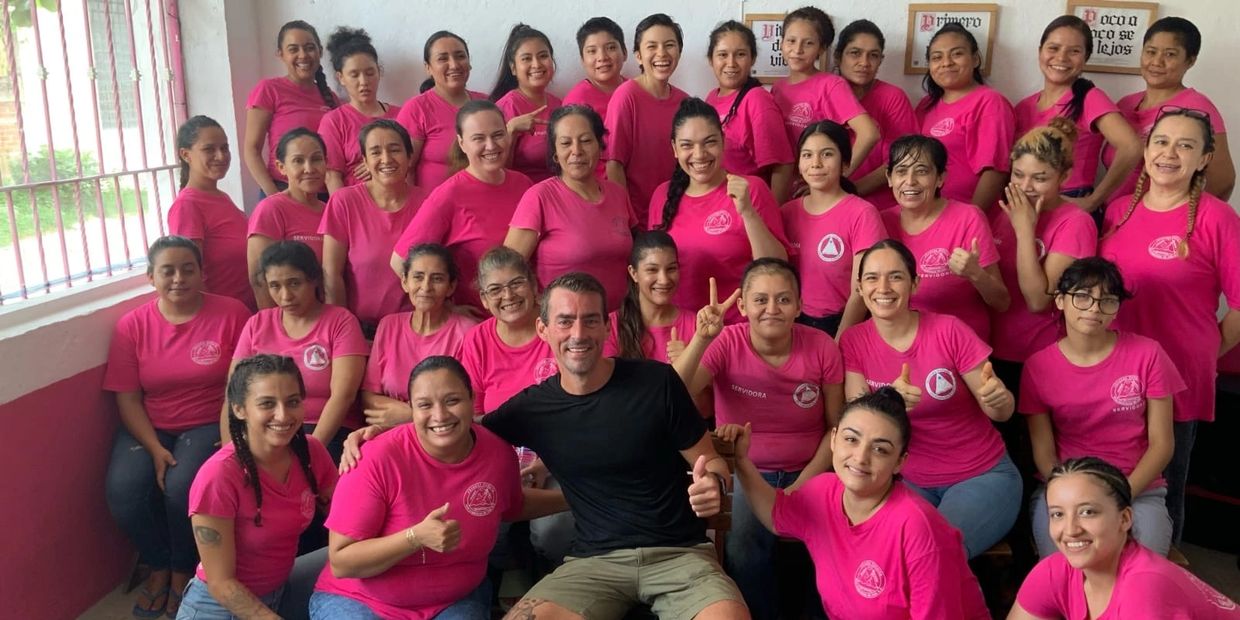 Group photo of smiling people wearing pink shirts with one man in black.