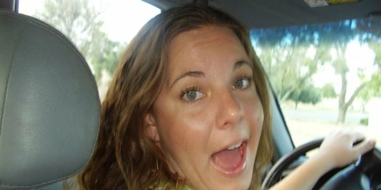 Woman smiling inside a car, looking back.