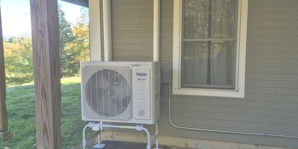 Outdoor Haier air conditioning unit installed on a house exterior.