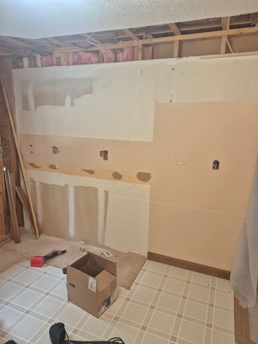 Room under renovation with drywall and tools.