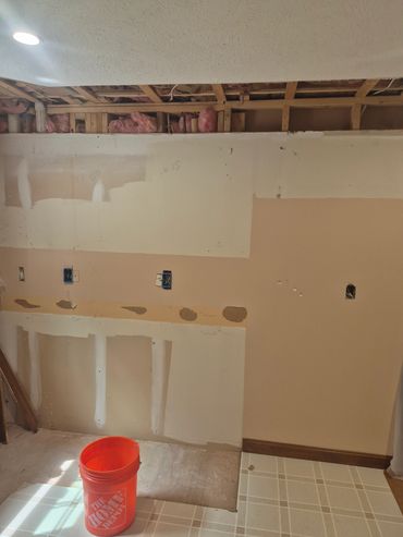Partially renovated room with exposed ceiling and an orange bucket.