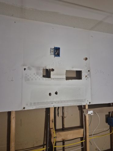 Wall with exposed electrical wiring and mounting bracket.