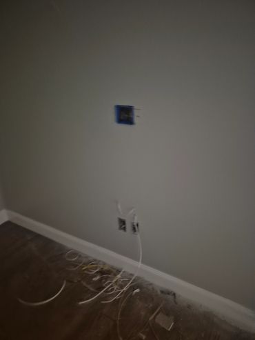 Wall with electrical outlets and scattered wires on the floor.