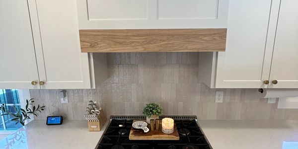 Modern kitchen stove with white cabinets and wooden accents.