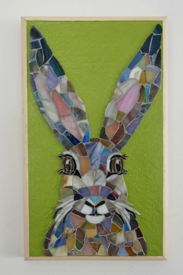 Colorful mosaic of a rabbit against a green background.