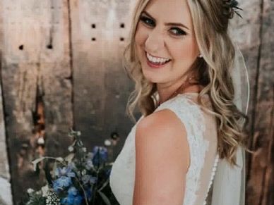 Bride in white dress holding bouquet, smiling joyfully.