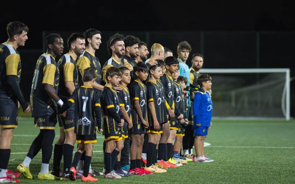 Soccer players and children line up on the field before a match.