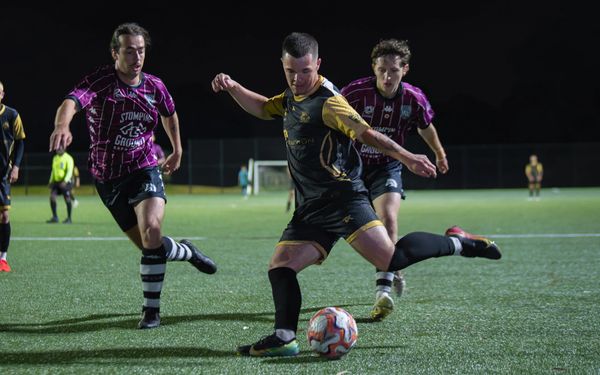 Soccer player in black and yellow prepares to kick the ball during a night match.
