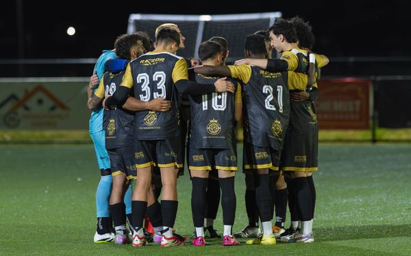 Soccer team huddling on field before a match at night.