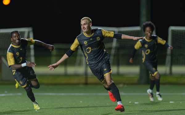 Soccer players celebrating a goal during a night match.