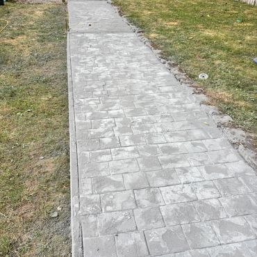 Newly paved stone pathway leading to a wooden gate.