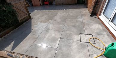 Freshly laid outdoor patio with large stone tiles and a garden hose.