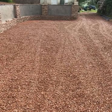 Newly laid gravel driveway with a retaining wall in the background.