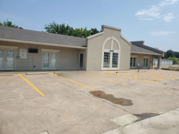 Empty parking lot in front of a beige commercial building.