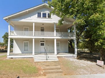 White two-story house with a balcony and steps.