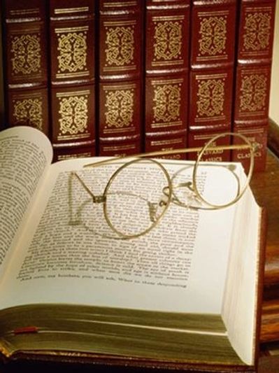 Vintage round spectacles resting on an open book, with a row of red leather-bound