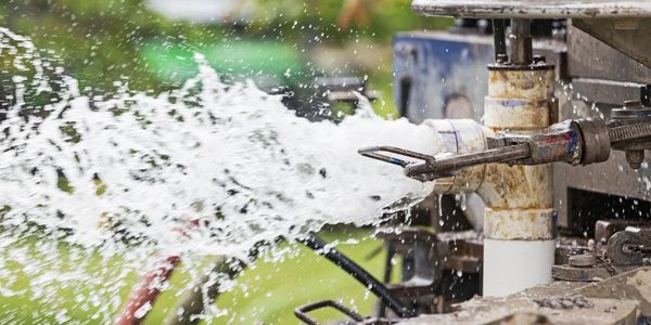 Water being blown out of the well with air pressure to determine flow rate, 